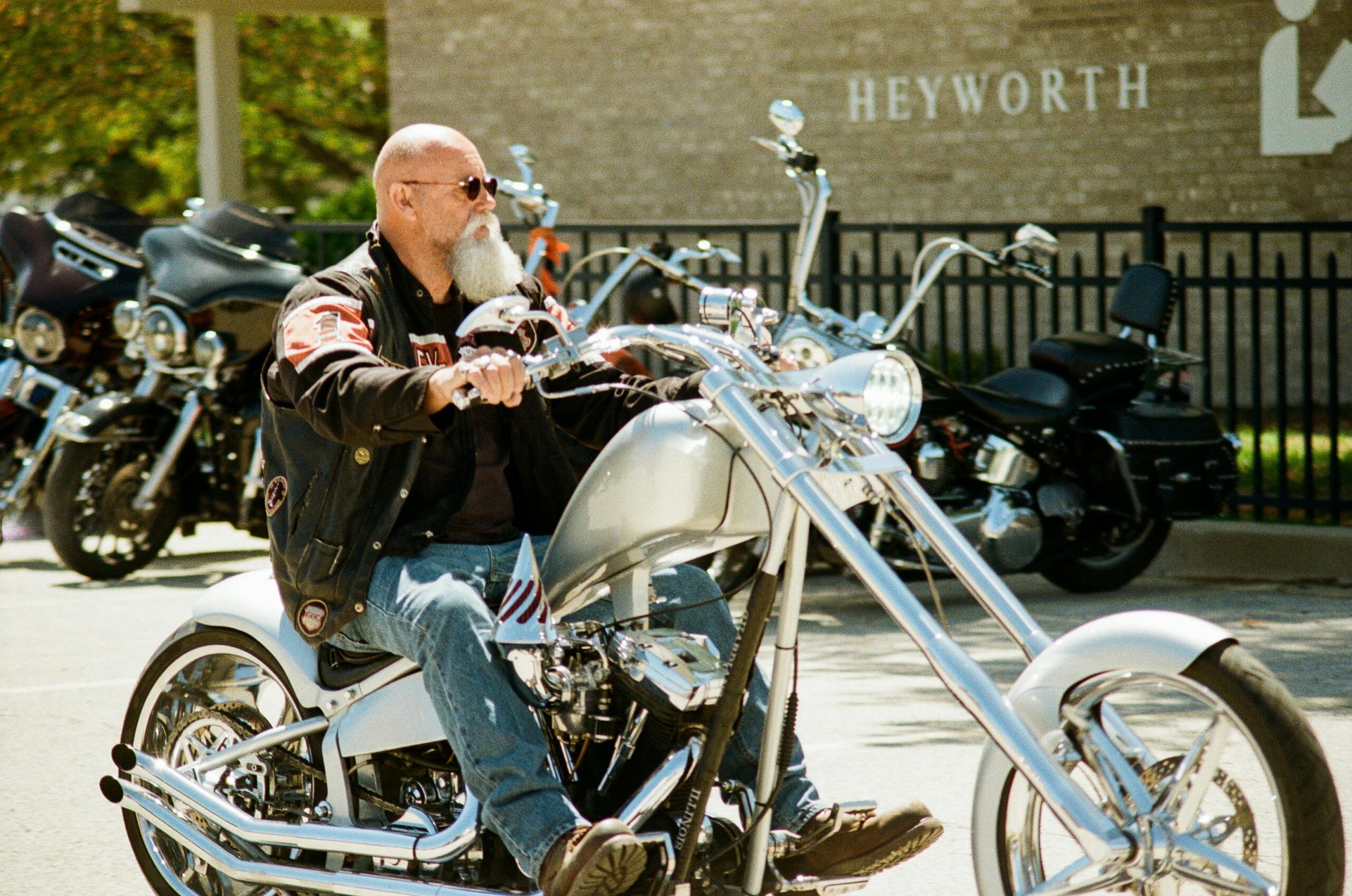 Ein Mann fährt an einem sonnigen Tag vor einem Café auf einem Custom-Chopper-Motorrad.