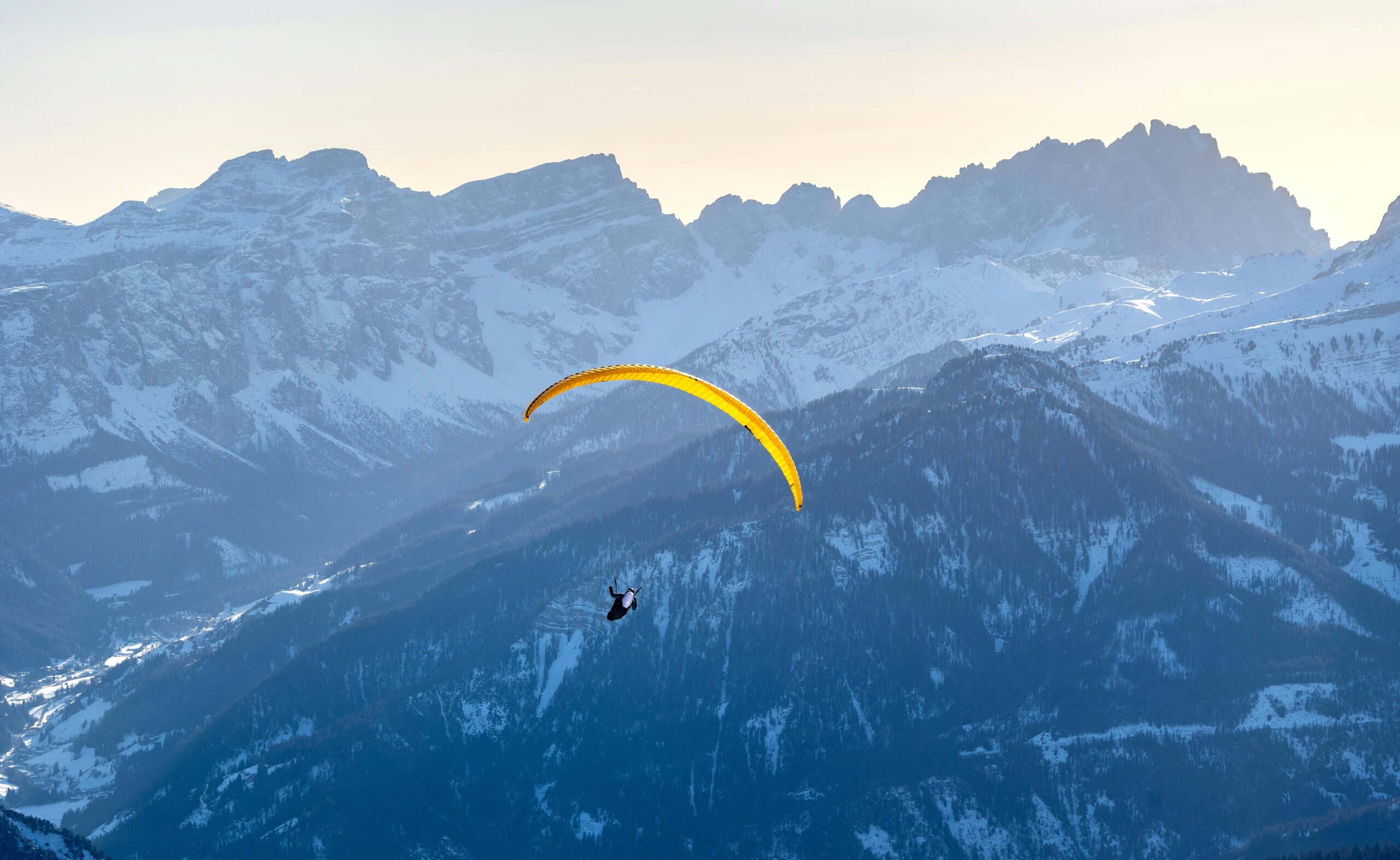 Ein Gleitschirm schwebt im Winter über den schneebedeckten Dolomiten im Trentino-Südtirol, Italien.