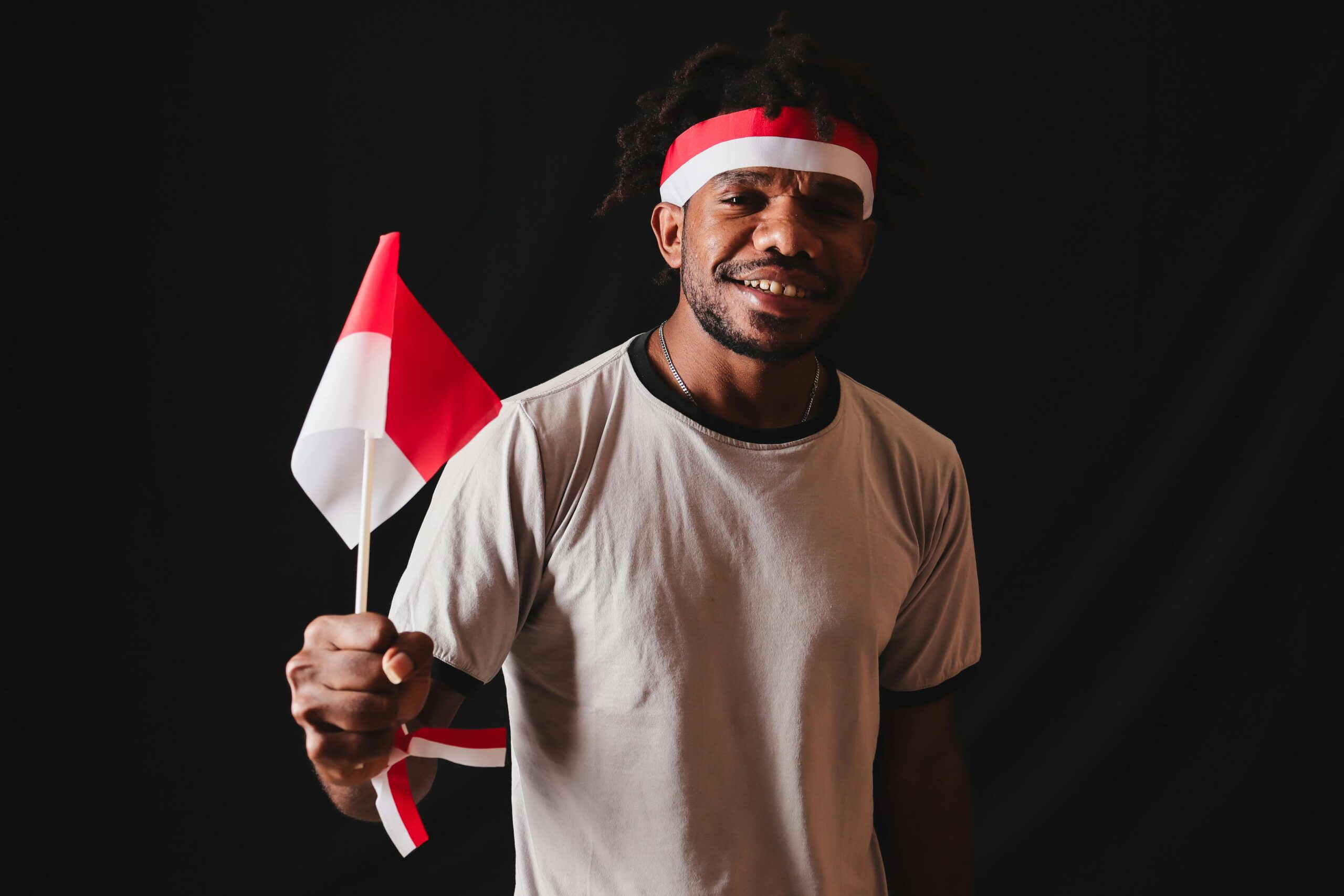Ein Papua hält in einem Studio stolz die indonesische Flagge und drückt damit seinen Nationalstolz aus.