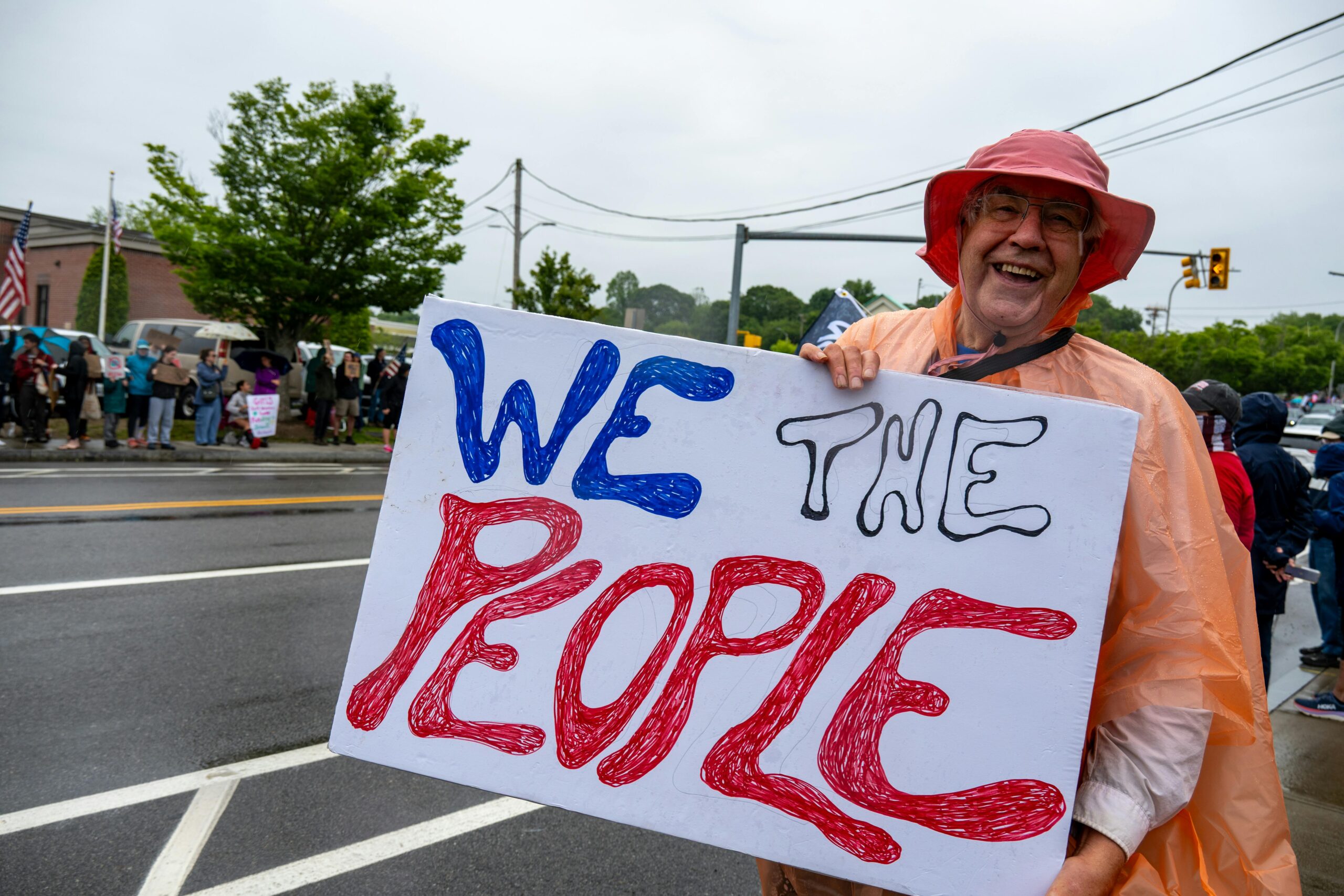 Ein lächelnder Demonstrant hält während einer Kundgebung in South Kingstown, Rhode Island, ein „We The People“-Schild.