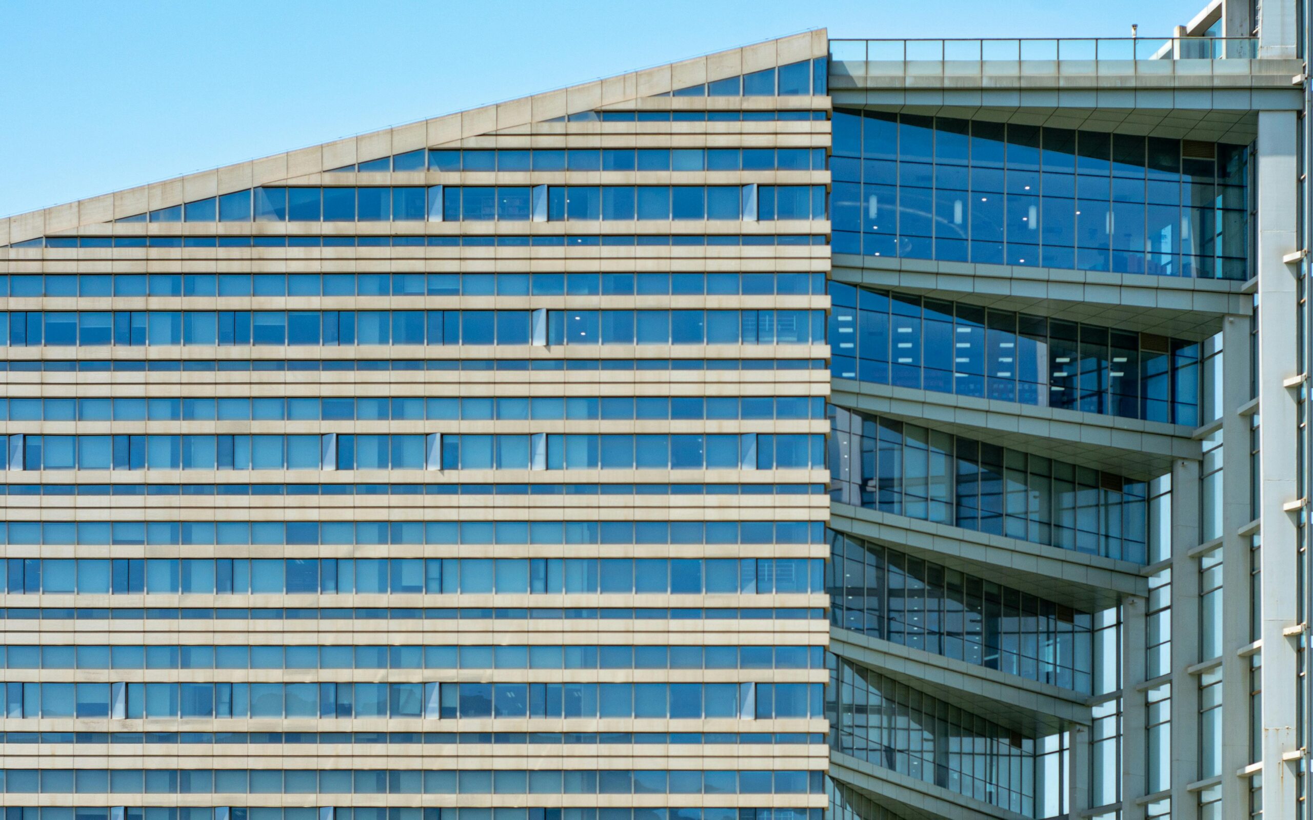 Nahaufnahme der Glasfassade eines modernen Gebäudes mit blauen Fenstern.
