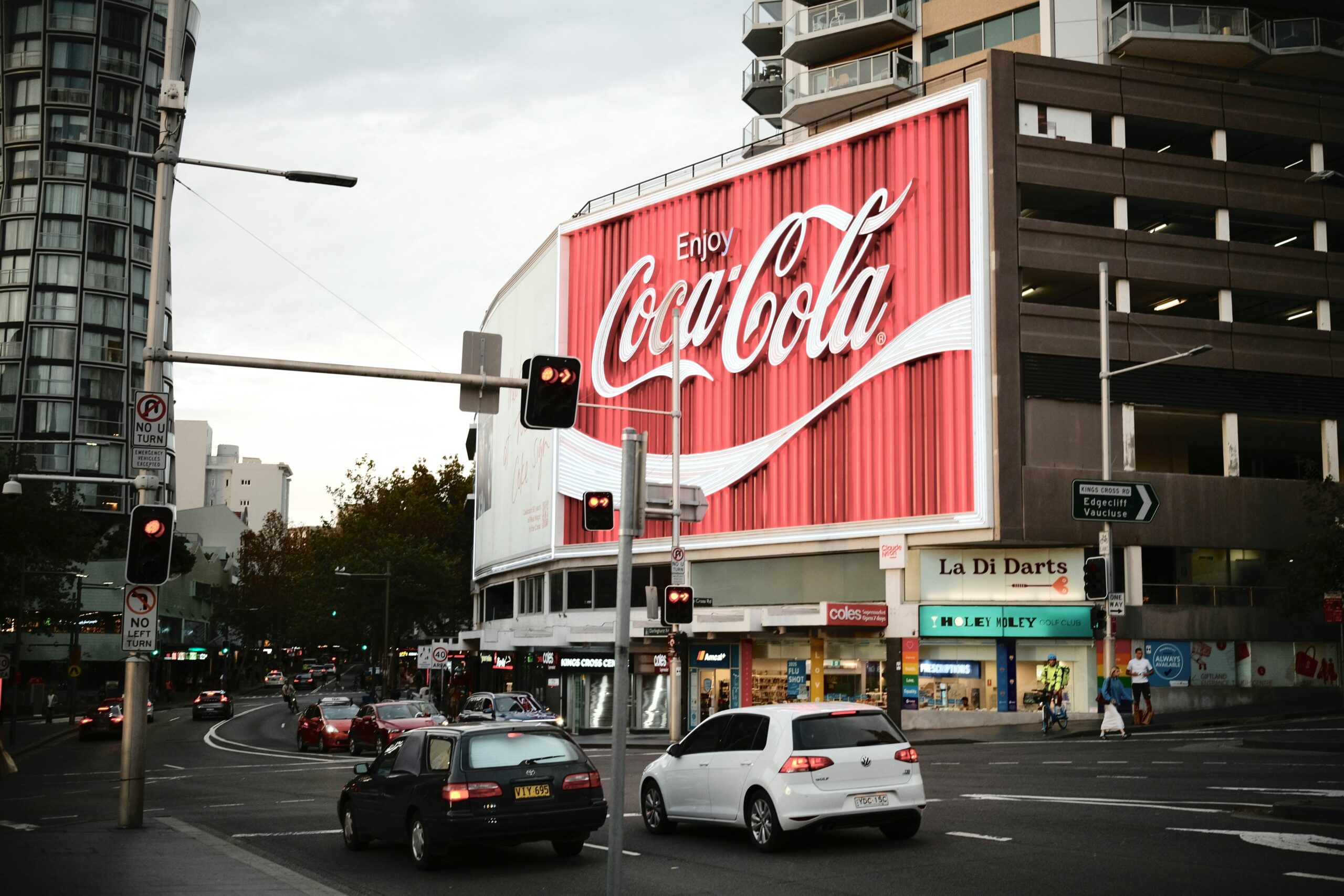 Sydneys berühmte Coca-Cola-Werbetafel erleuchtet eine belebte Straßenecke.
