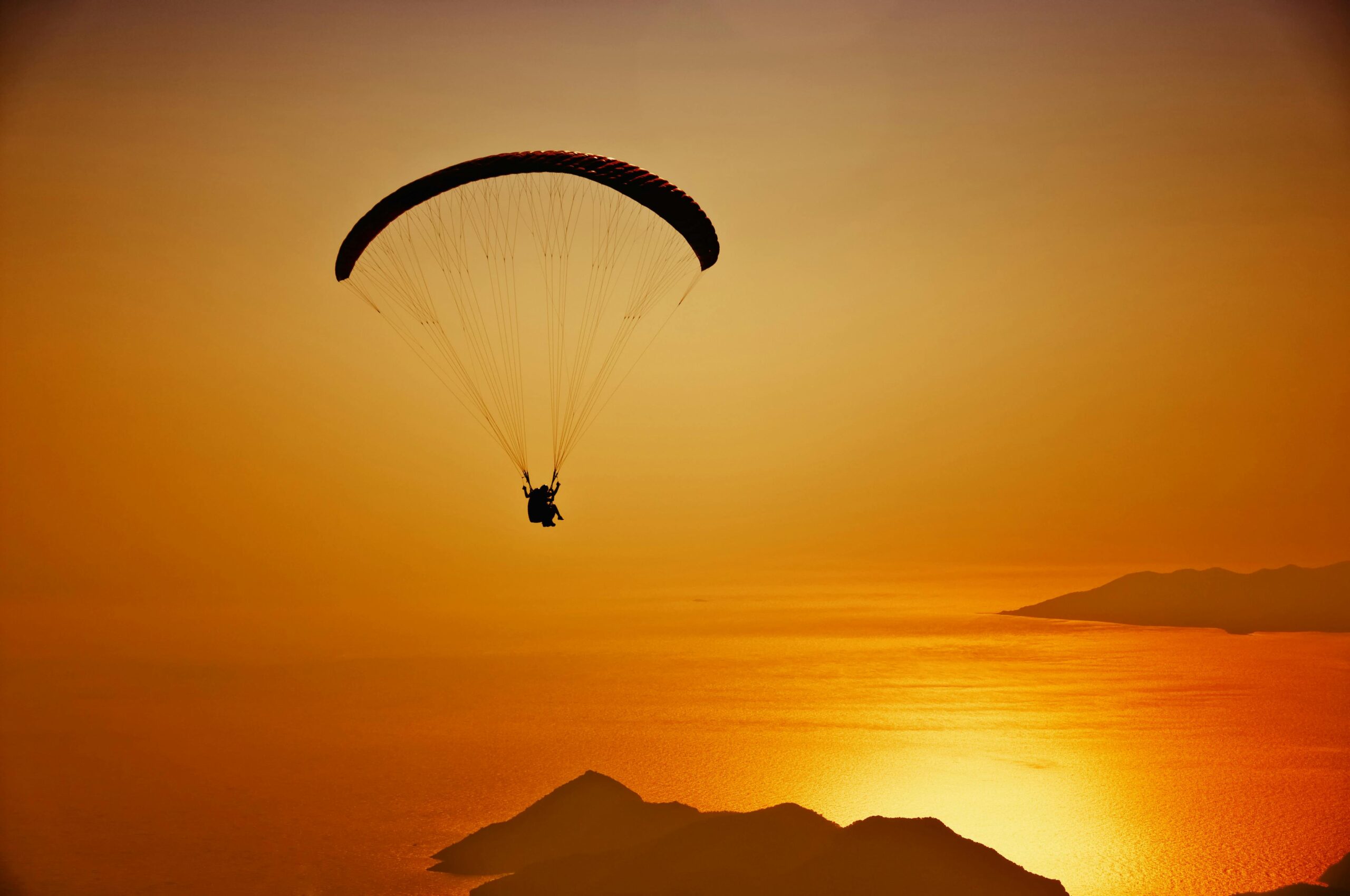 Während eines goldenen Sonnenuntergangs schwebt ein Gleitschirm über dem schimmernden Wasser von Ölüdeniz in der Türkei.