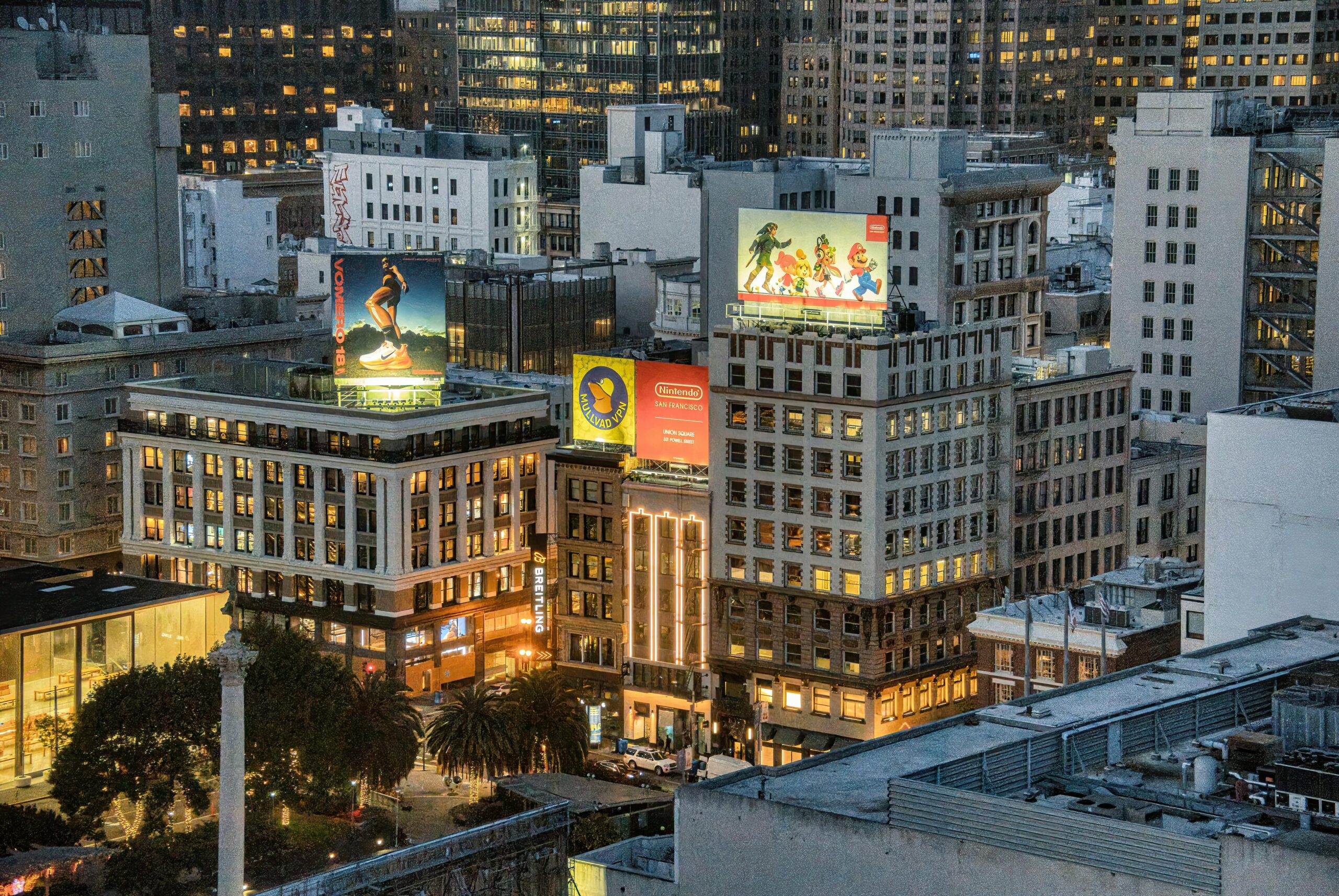 Abendansicht der Gebäude von San Francisco mit leuchtenden Werbetafeln und den Lichtern der Stadt.