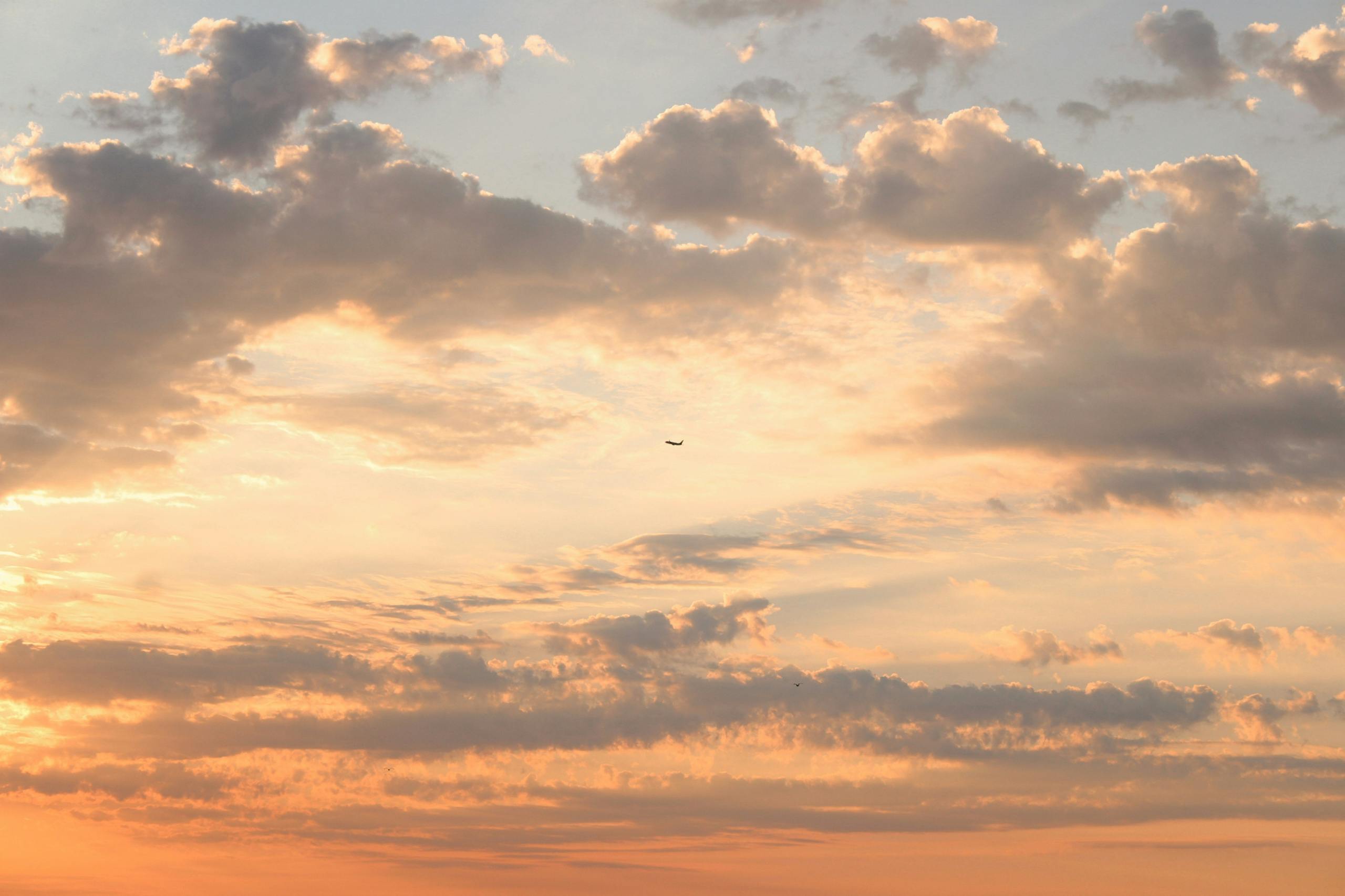 Dramatischer Sonnenuntergang mit einem Flugzeug, das durch leuchtende Wolken fliegt und heitere Schönheit einfängt.