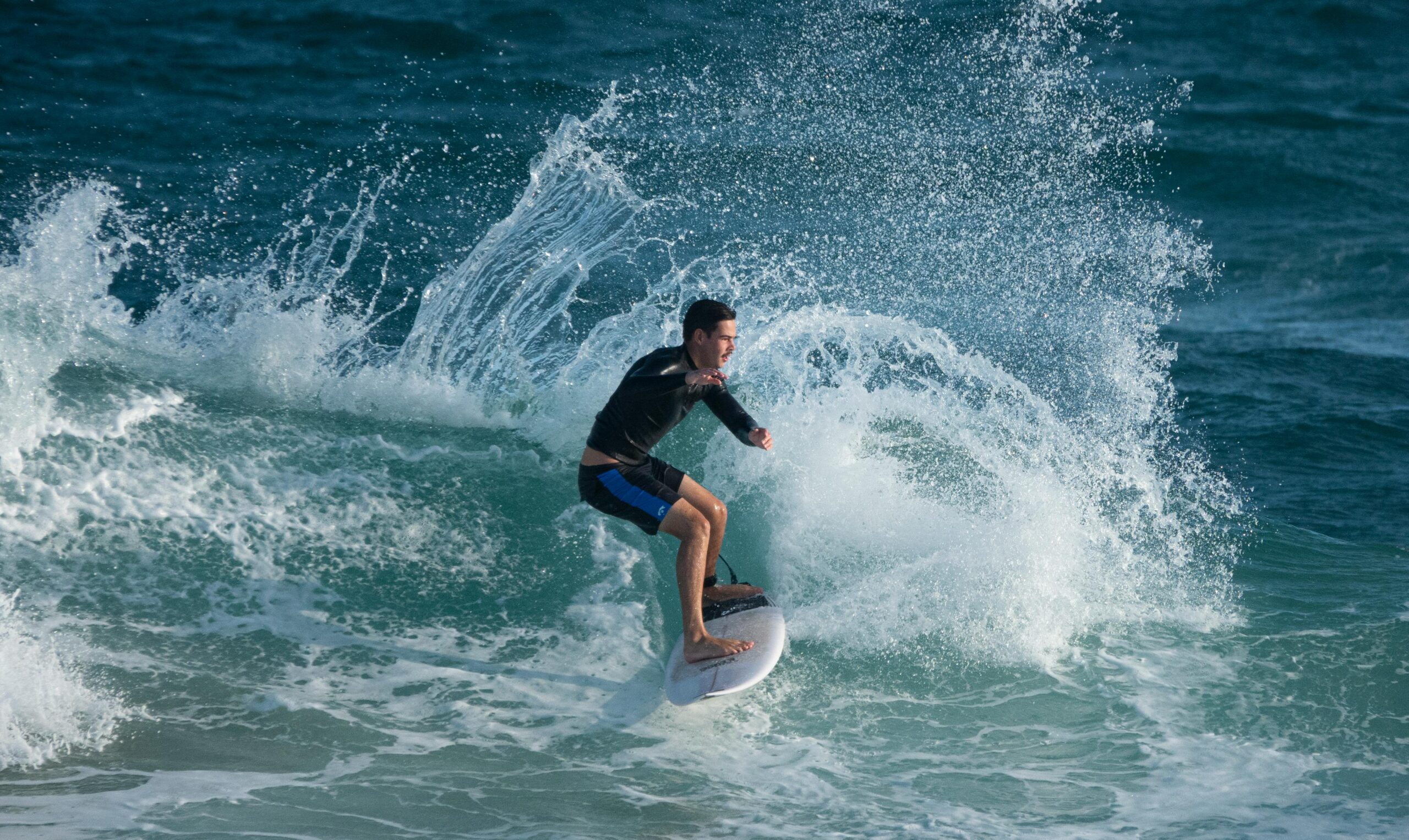 Junger Surfer bezwingt die Wellen in Merewether, Australien, mit einer aufregenden Ocean-Splash-Action.