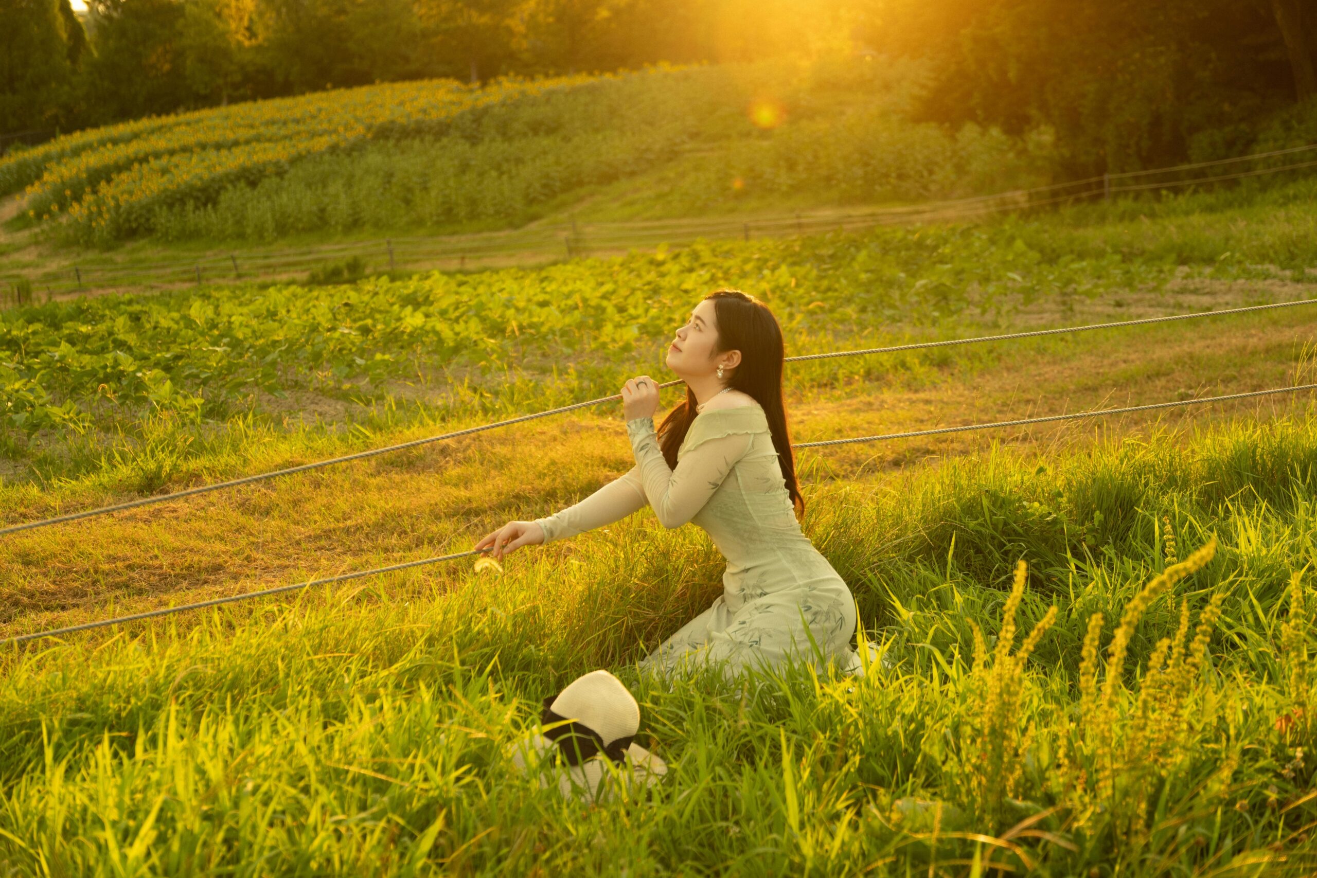 Junge Frau auf einem ländlichen Feld bei Sonnenuntergang, die die Natur mit Ruhe und Frieden genießt.