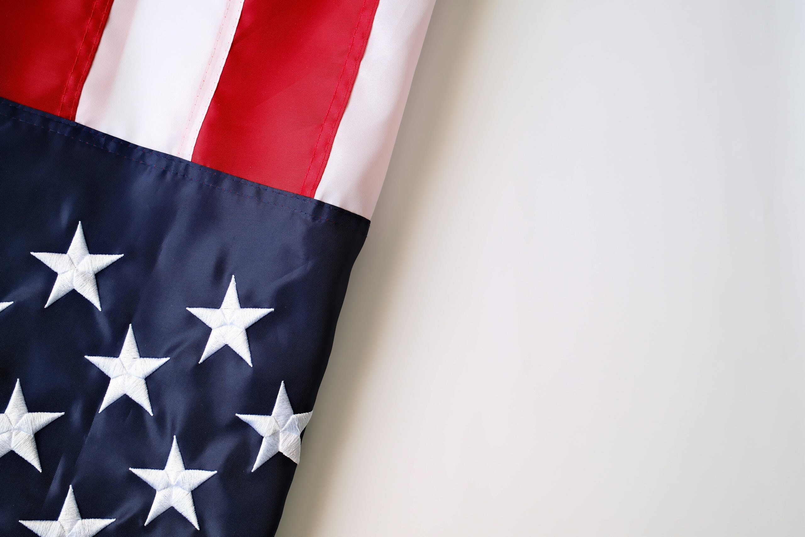Detaillierte Nahaufnahme der US-Flagge mit Sternen und Streifen auf neutralem Hintergrund.