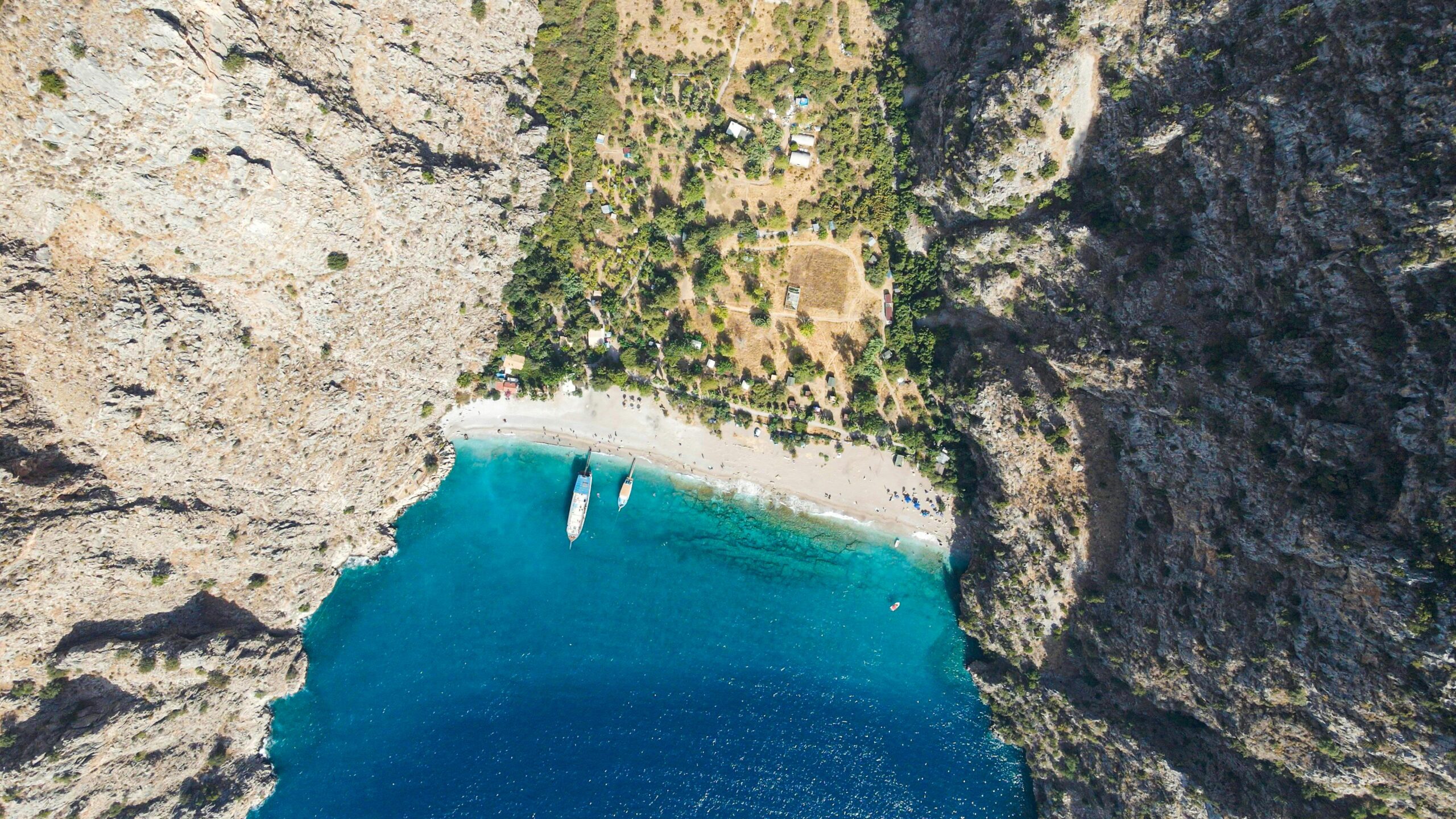 Eine atemberaubende Luftaufnahme eines wunderschönen Strandes in Muğla, Türkei, umgeben von Klippen.
