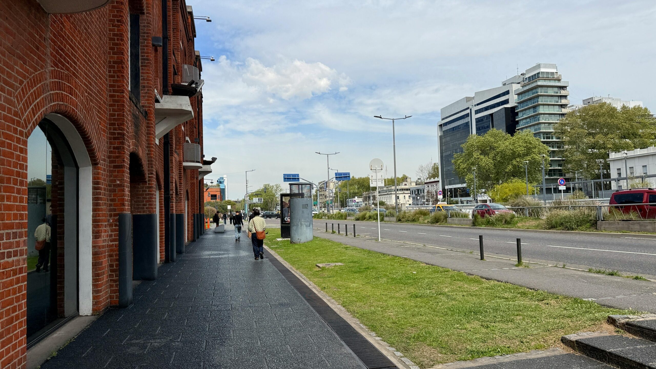 Stadtstraße mit roten Backsteingebäuden und modernen Hochhäusern unter blauem Himmel.