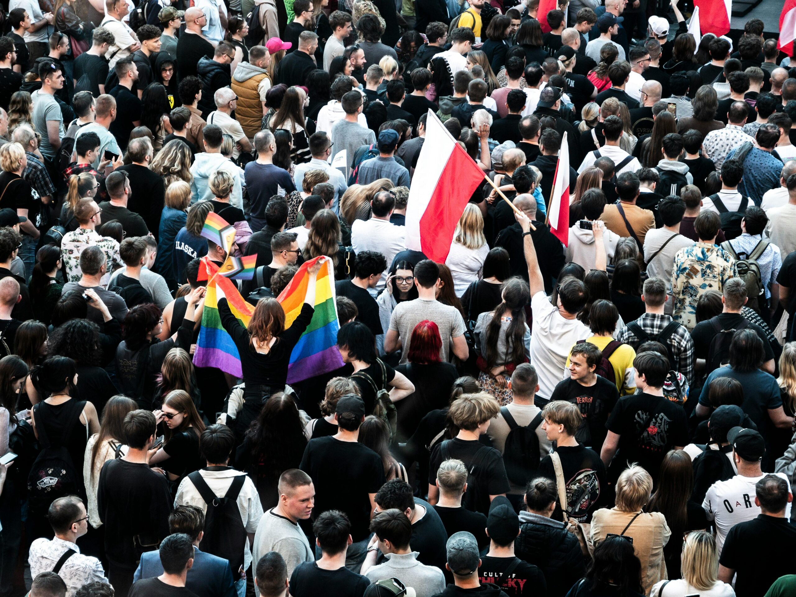 Eine große Menschenmenge versammelt sich mit Regenbogen- und Nationalflaggen und feiert Vielfalt und Einheit.