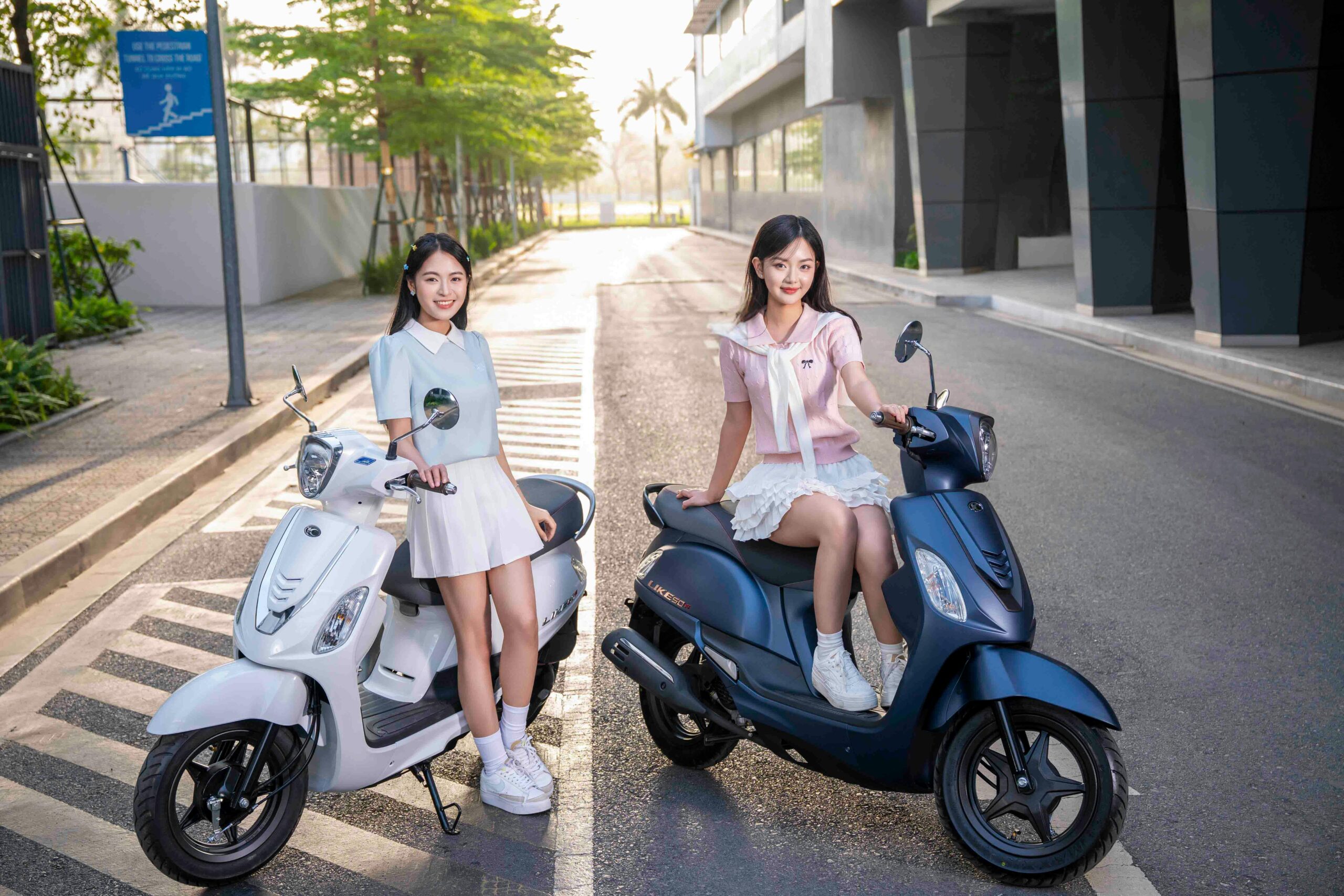 Zwei junge Frauen auf Motorrollern genießen eine Tagesfahrt in einer modernen Stadt in Vietnam.