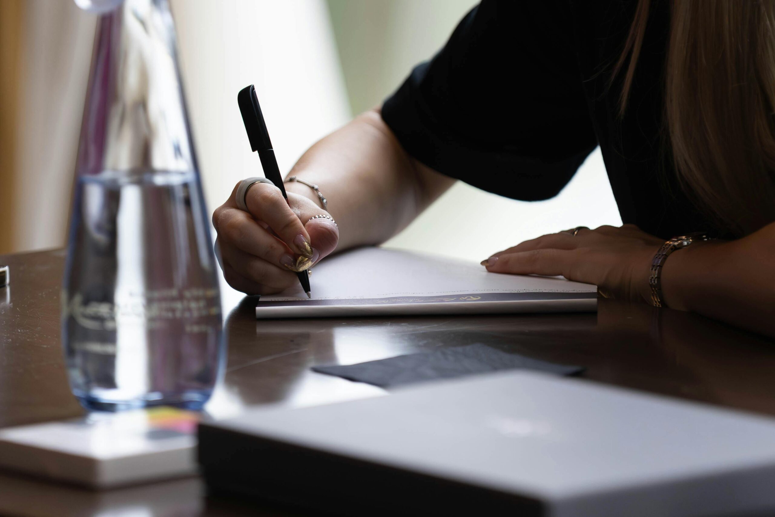 Nahaufnahme einer Frau, die sich drinnen mit Stift und Notizbuch Notizen macht. Ideal für Geschäfts- oder Bildungsinhalte.