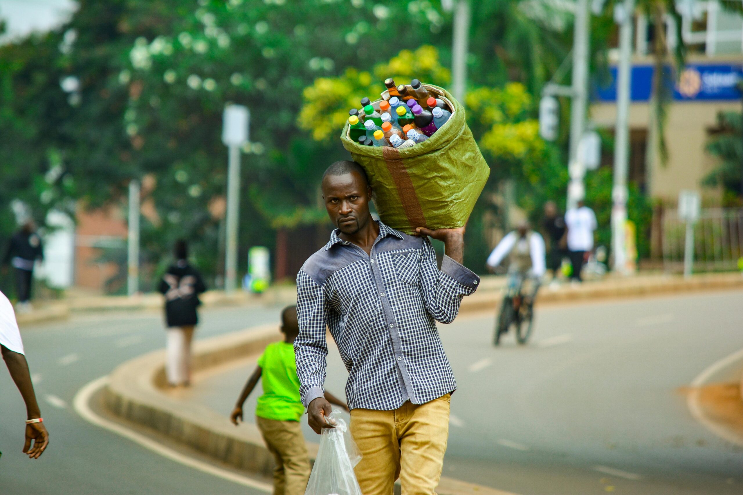 Ein Mann trägt ein Bündel Flaschen in Kampala, Uganda, und zeigt das pulsierende Straßenleben.