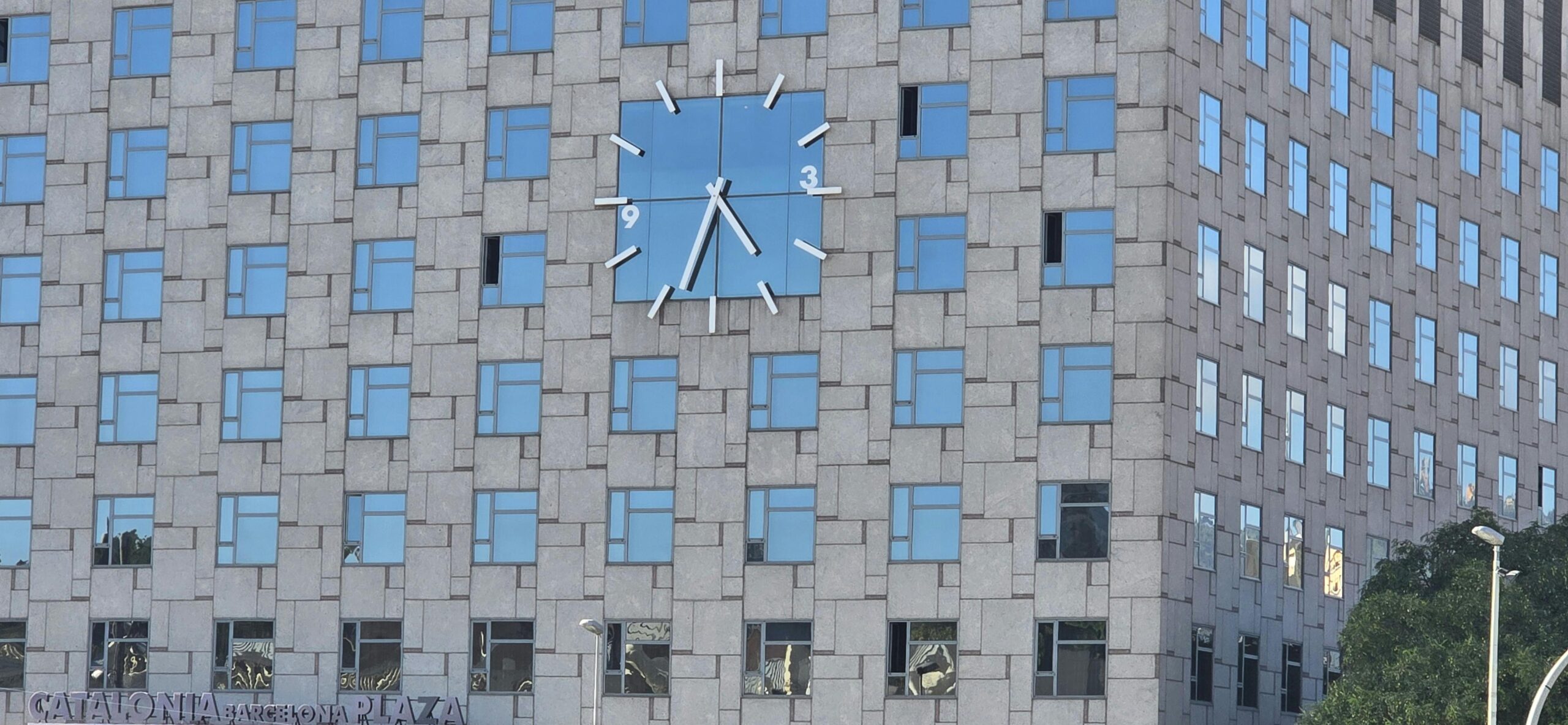 Fassade des Catalonia Barcelona Plaza mit Fenstern und einem markanten Uhrendesign.