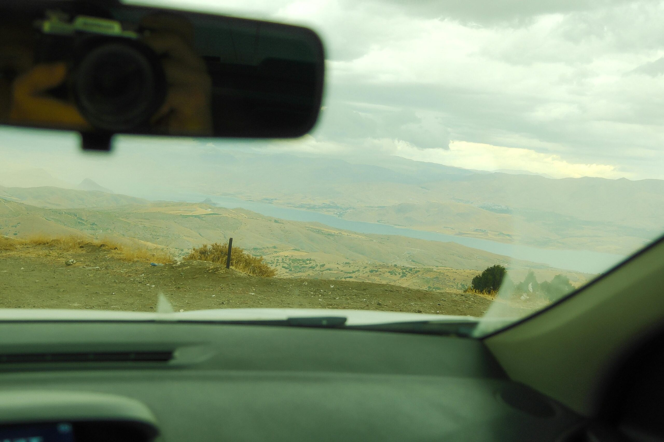 Der Blick auf einen See und Berge durch die Windschutzscheibe eines Autos vermittelt das Gefühl, etwas Neues zu entdecken.