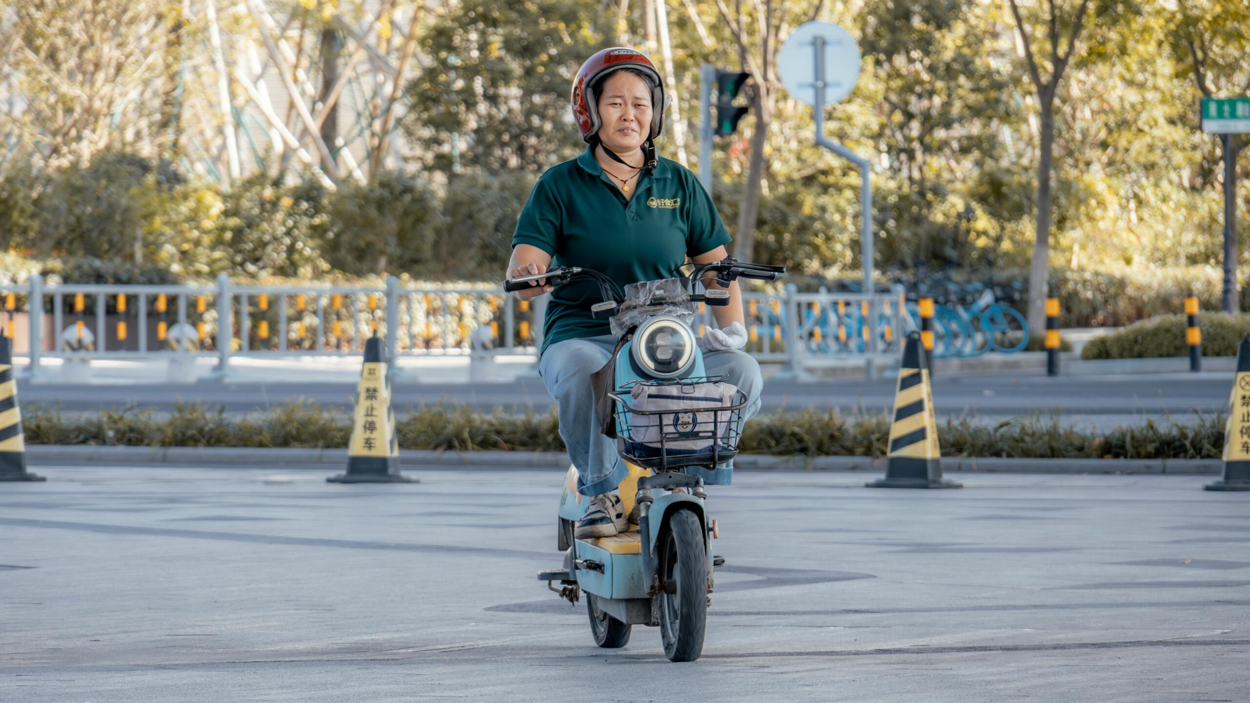 Frau fährt an einem sonnigen Tag im Freien in der Stadt mit einem Elektroroller.