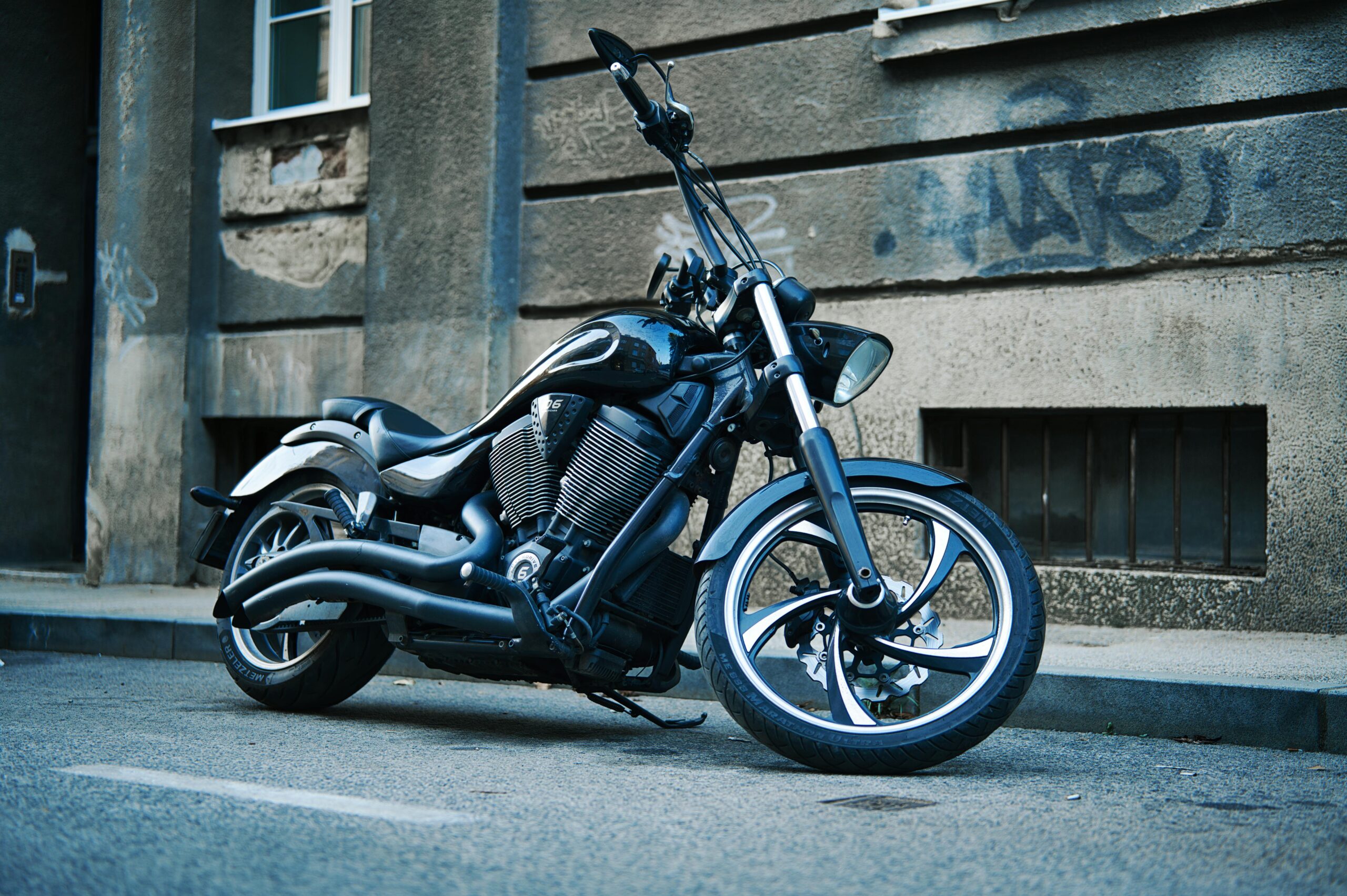 Stilvolles schwarzes Motorrad, das in einer mit Graffiti gesäumten Straße geparkt ist, der Inbegriff des urbanen Stils.