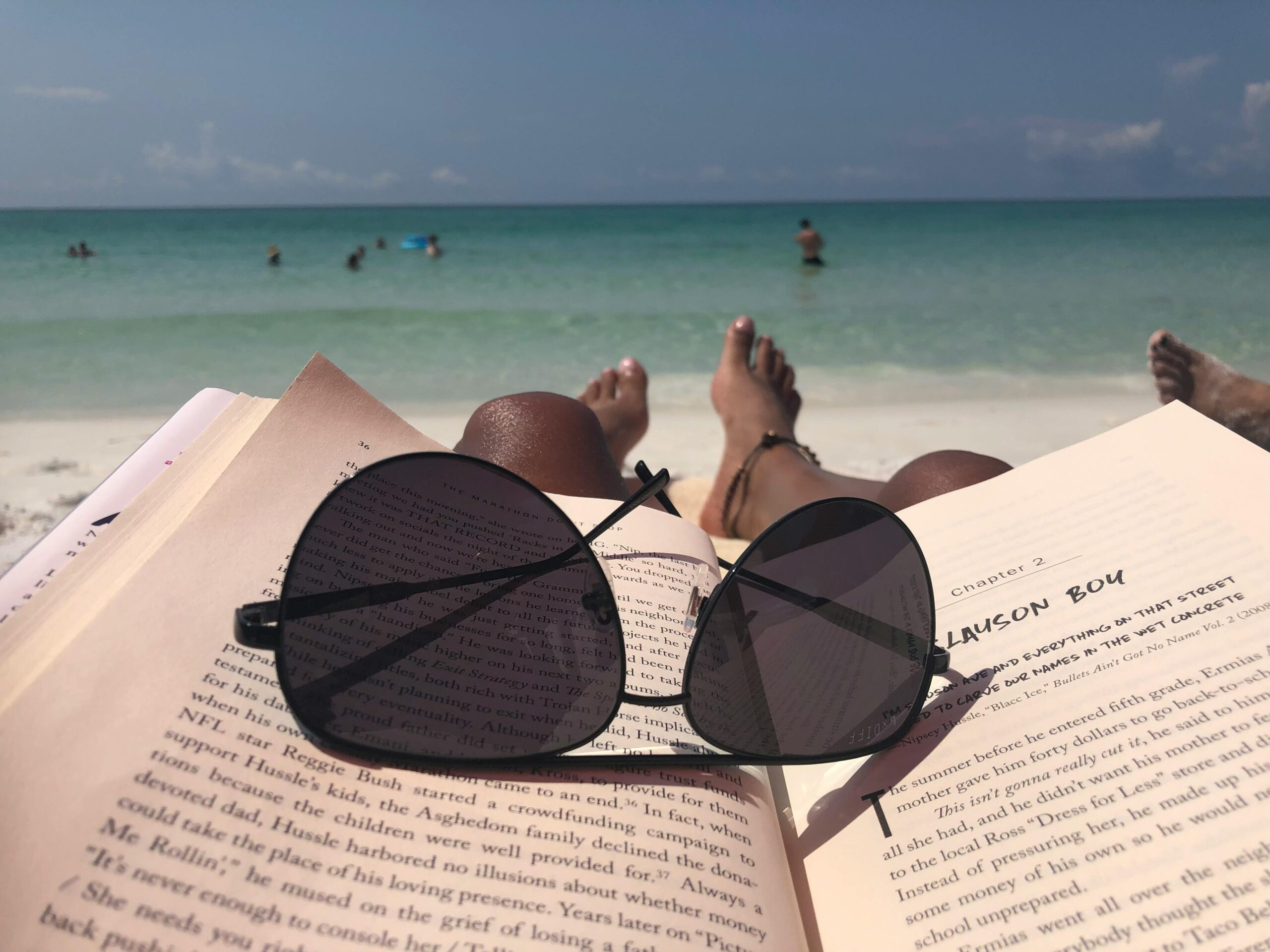 Gemütliche Strandentspannung mit einem Buch und einer Sonnenbrille am Meer.